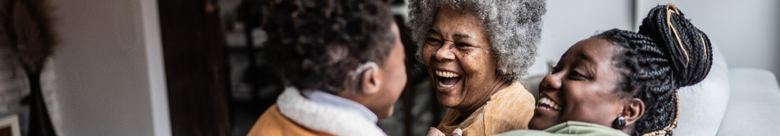 Three generations of woman in their home laughing together