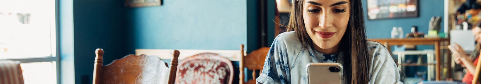 Woman in coffee shop sitting a table and looking at her smart phone