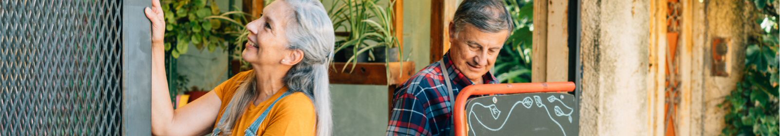 Mature woman and man working outside of their plant nursery