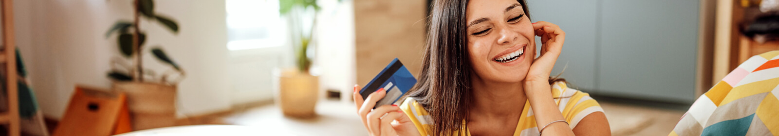 Woman in her home smiling while holding her debit card