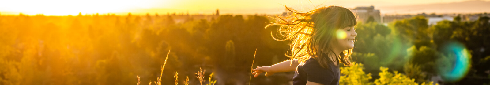 Young girl smiling while playing in a field at golden hour