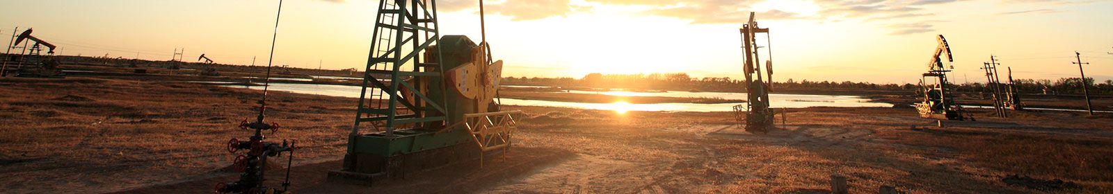 Construction machines in a plowed field at sunrise