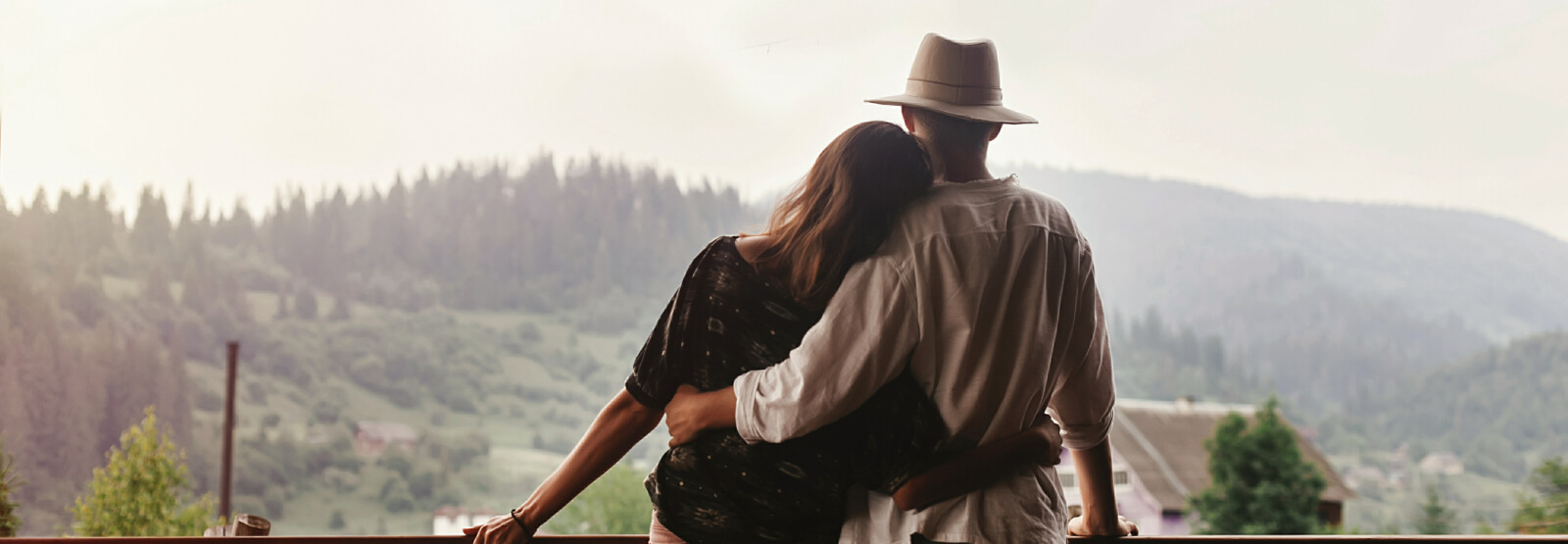 Couple holding each other on a porch while looking at mountain scape