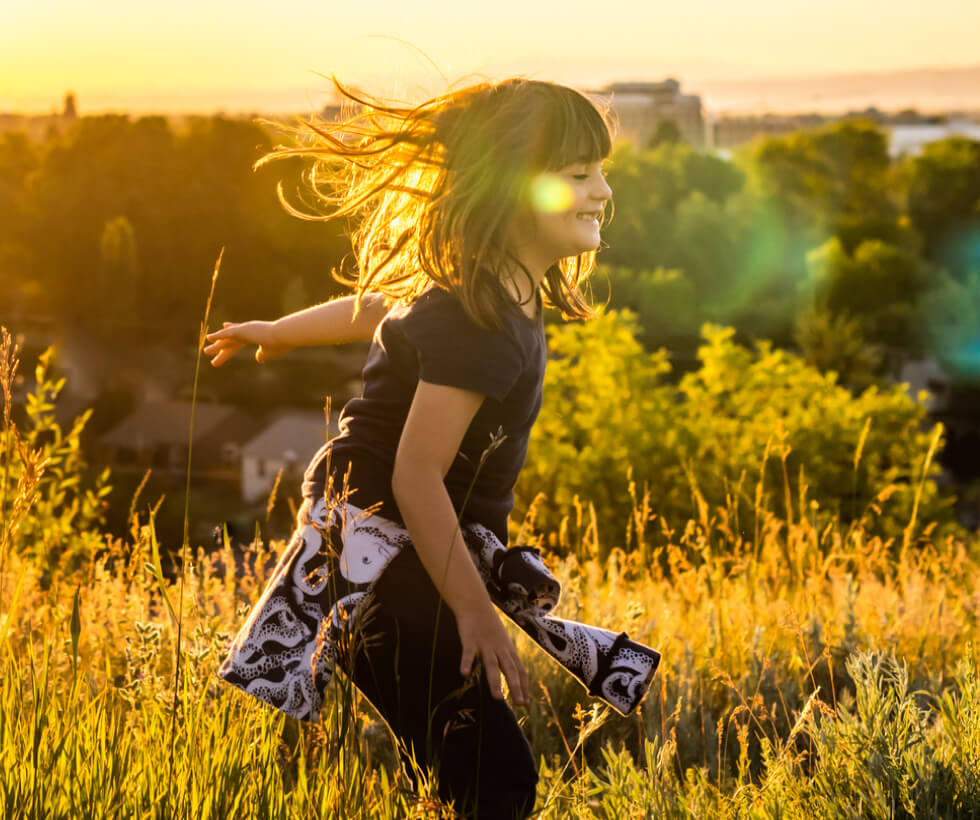 Young girl smiling and playing in a field at golden hour