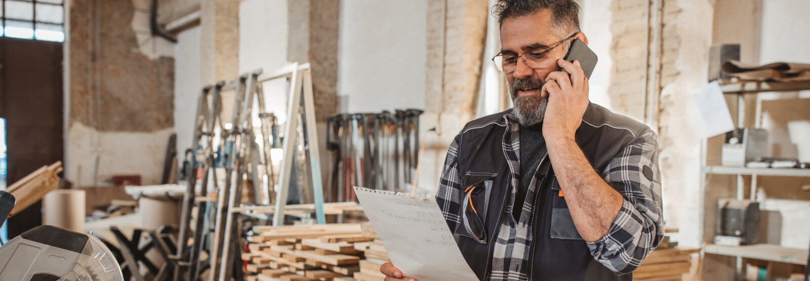 Business man in work shop while talking on the phone and looking at documents